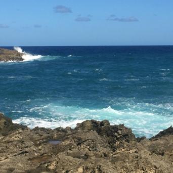 a man standing on a rocky beach next to the ocean