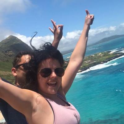 a woman in sunglasses standing in front of a body of water