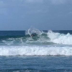 a man riding a wave on a surfboard in the ocean with Southern Ocean in the background