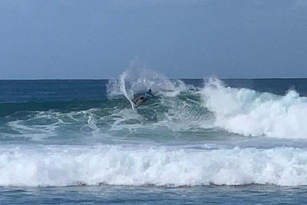 a man riding a wave on a surfboard in the ocean with Southern Ocean in the background
