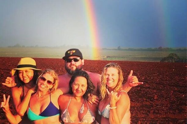 a group of people posing for a picture with a rainbow in the background