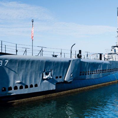 a boat is docked next to a body of water with USS Bowfin (SS-287) in the background